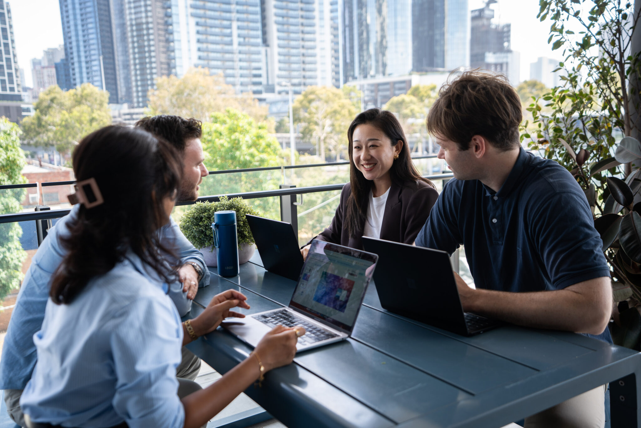 Adcore team members working together with laptops on an office balcony
